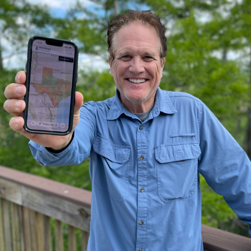 Well Water Finders CEO holding mobile phone with the Texas Well Water Map app displayed.