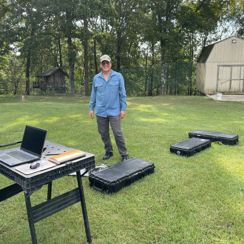 Andrew from Well Water Finders with survey equipment on a grassy property, helping a landowner confirm water availability before drilling.
