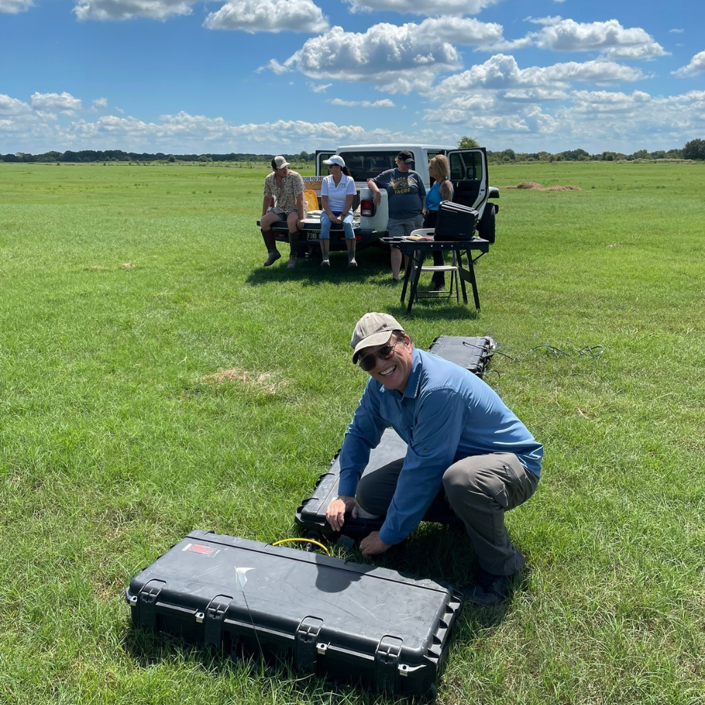 Andrew from Well Water Finders taking groundwater location readings while realtors standby to learn the results.